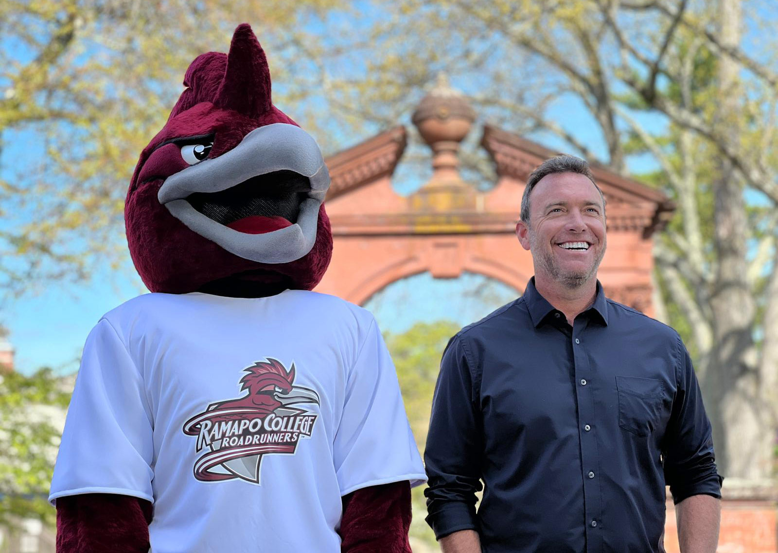 Alex Boylan and СƵ's Roadrunner mascot standing together outside of the Havemeyer Arch 